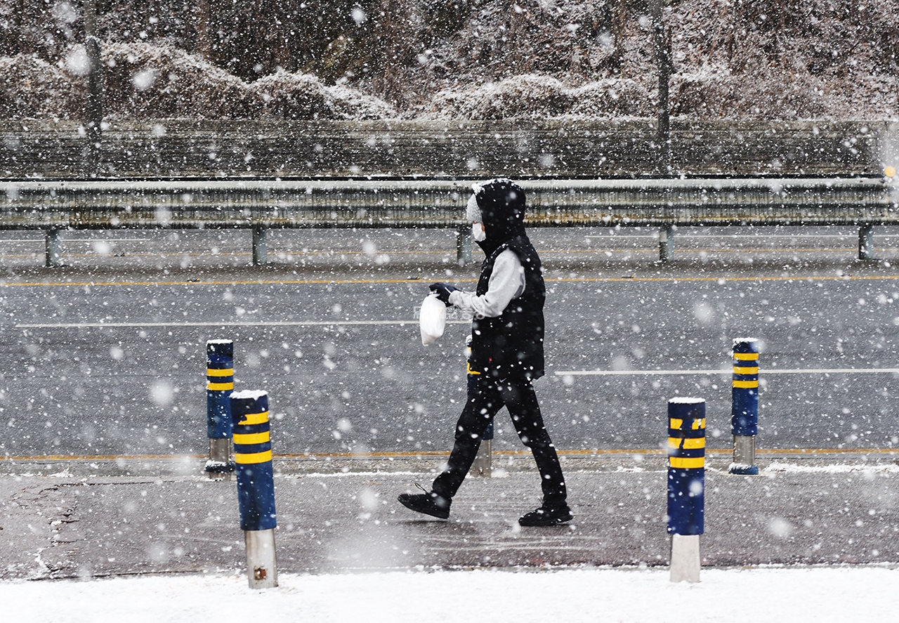 눈이 내리는 가운데 한 시민이 천안 쌍용동 거리를 걷고 있다.(사진=채원상 기자)